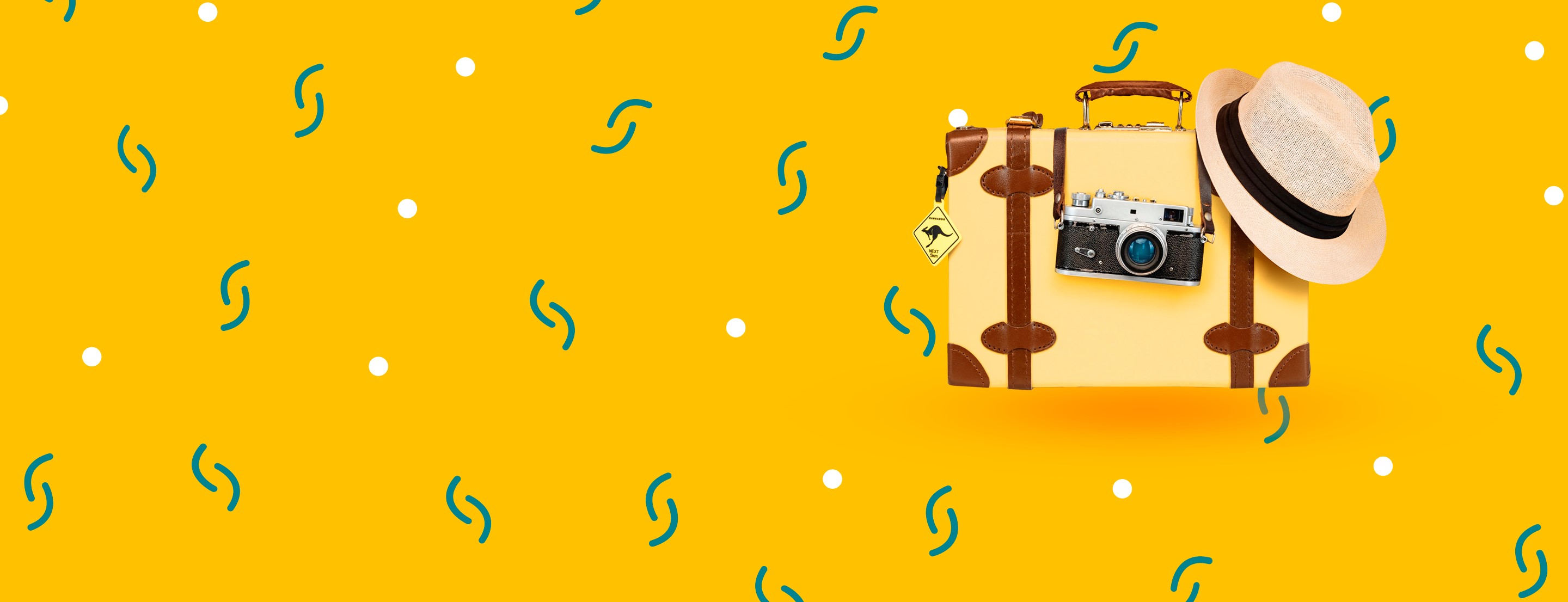 Valise jaune avec un appareil photo et un chapeau sur fond jaune à motifs colorés.