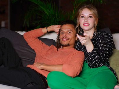 un couple regarde la télé depuis un canapé