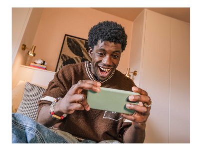 Homme souriant joue sur son téléphone dans un salon chaleureux.