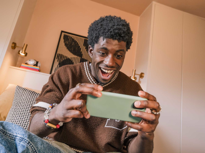Homme souriant joue sur son téléphone dans un salon chaleureux.