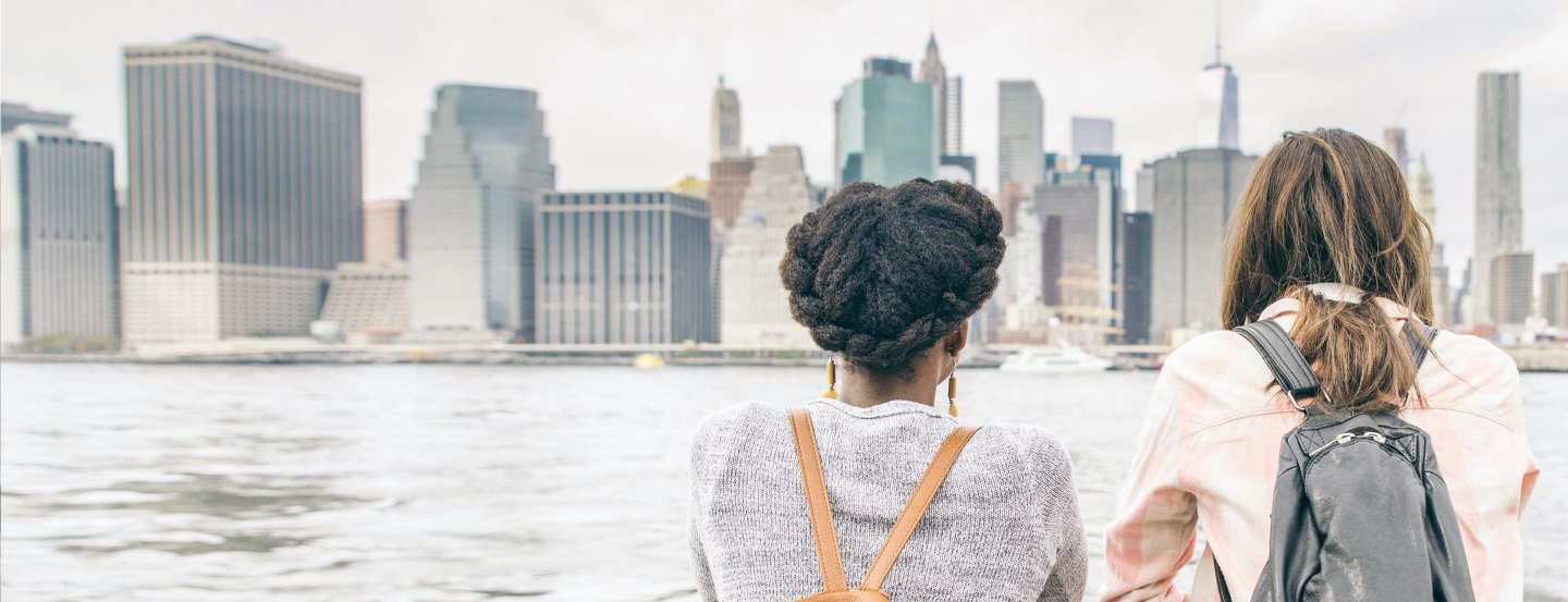 Deux femmes regardant Manhattan depuis un bateau, avec des gratte-ciel en arrière-plan.