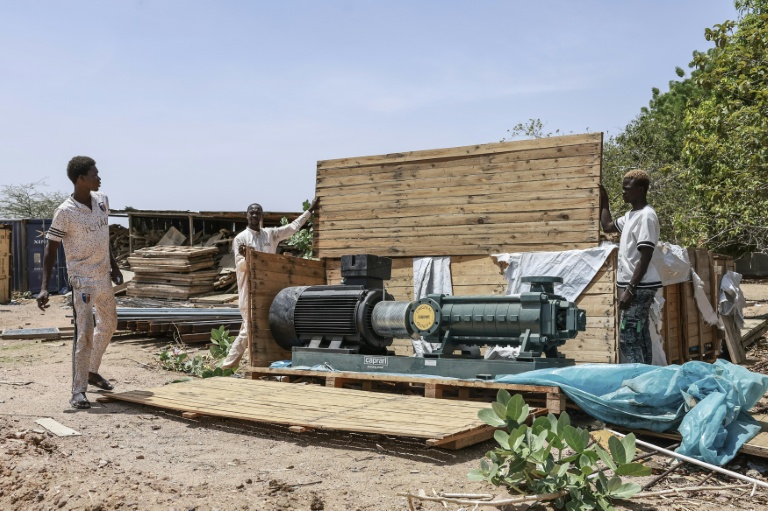 Des ouvriers ouvrent une caisse en bois contenant une pompe de surpression sur le chantier de la station de pompage d'eau de Biteha (Tchad), le 13 juillet 2026