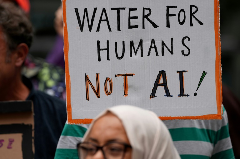 Une personne brandit une pancarte indiquant "De l'eau pour les humains, pas pour l'IA" lors d'une manifestation contre l'approbation d'un centre de données prévu dans les plans de réaménagement du quartier de Brick Lane, le 4 septembre 2026 à Londres