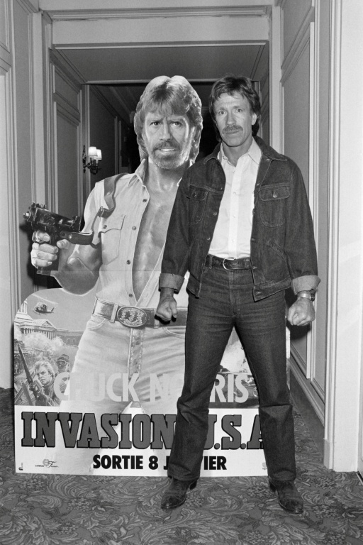 Chuck Norris pose devant l'affiche du film "Invasion USA", à Paris, le 27 novembre 1985