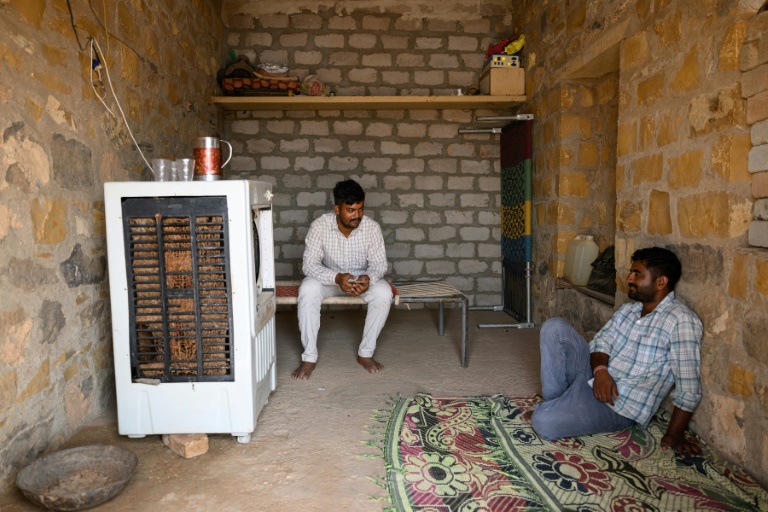 Deux hommes devant un climatiseur, par 42°C, le 29 mai 2026 à Sanwata, au Rajasthan, en Inde