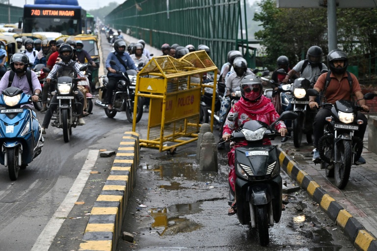 Des motocyclistes roulent sur un trottoir pour piétons le long d'un pont à New Delhi, le 8 juillet 2026 en Inde