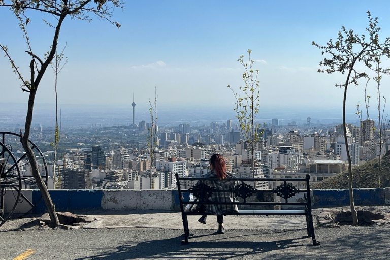 Une femme assise sur un banc au parc Pardisan, surplombant Téhéran, le 22 avril 2026 en Iran