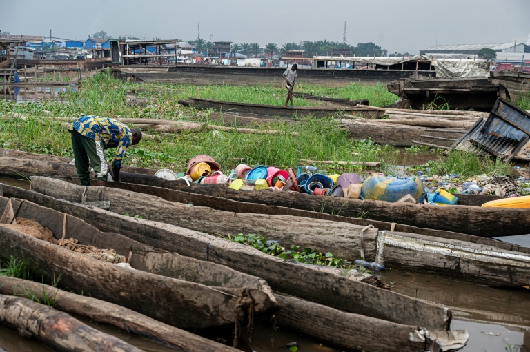 Un pêcheur trie dans une pirogue des objets en plastique ramassés sur les rives du fleuve Congo à Kinshasa, le 27 avril 2026 en RDC