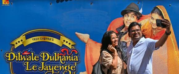 Des cinéphiles se prennent en photo devant une affiche du film "Dilwale Dulhania Le Jayenge" diffusé quotidiennement au cinéma Maratha Mandir de Bombay, le 11 octobre 2025 Des cinéphiles se prennent en photo devant une affiche du film "Dilwale Dulhania Le Jayenge" diffusé quotidiennement au cinéma Maratha Mandir de Bombay, le 11 octobre 2025