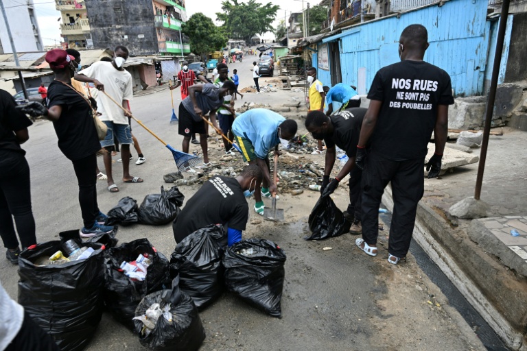 Des jeunes bénévoles de l'association "Clean Street" nettoient les caniveaux obstrués par des déchets et autres plastiques à Attecoubé, un quartier populaire d'Abidjan, le 22 mars 2026 en Côte d'Ivoire