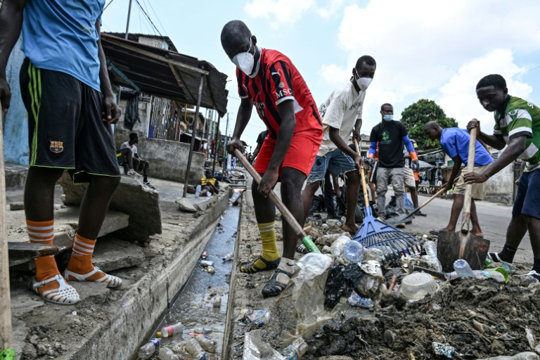 Des jeunes bénévoles récurent des caniveaux saturés de déchets à Abidjan, en Côte d'Ivoire, le 22 mars 2026