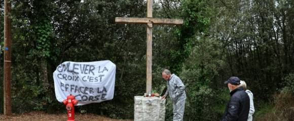 Une banderole à côté d'une croix en bois objet de polémiques à l'entrée du village de Quasquara, le 14 octobre 2025 en Corse-du-Sud Une banderole à côté d'une croix en bois objet de polémiques à l'entrée du village de Quasquara, le 14 octobre 2025 en Corse-du-Sud