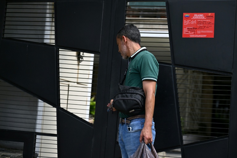 Un habitant quitte les lieux après qu'une inspection officielle a déclaré son immeuble inhabitable (panneau rouge) à Caracas, après le double séisme du 24 juin, le 6 juillet 2026 au Venezuela