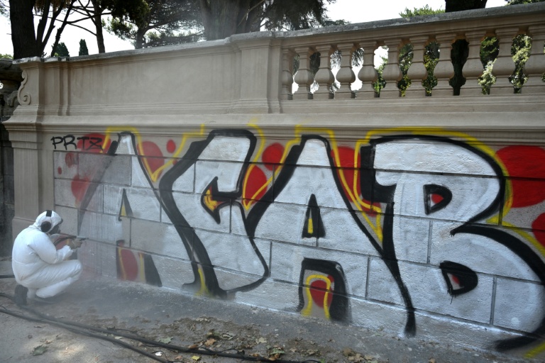 Valerio Tuveri, connu sur les réseaux comme "le gars qui nettoie Rome", efface un graffiti le long d'un mur de la Villa Sciarra, à Rome, le 27 juillet 2026