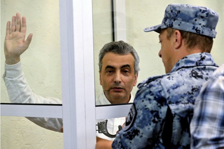 Un huissier passe les menottes à Lev Chlosberg, vice-président du parti antiguerre russe Iabloko, condamné à 11 ans de prison pour avoir critiqué l'offensive de Moscou en Ukraine, au tribunal de Pskov, dans le nord-ouest de la Russie, le 17 août 2026