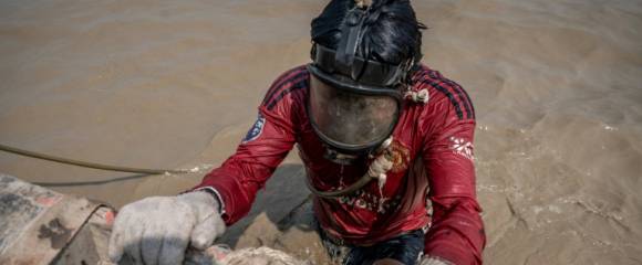 Un homme plonge dans les eaux boueuses du fleuve Yangon pour remonter des épaves, le 27 février 2024 à Rangoun, en Birmanie